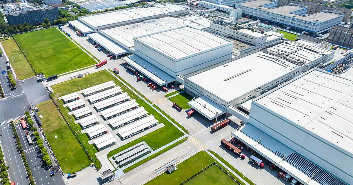 Aerial view of a factory surrounded by numerous trucks, showcasing industrial activity and logistics operations.