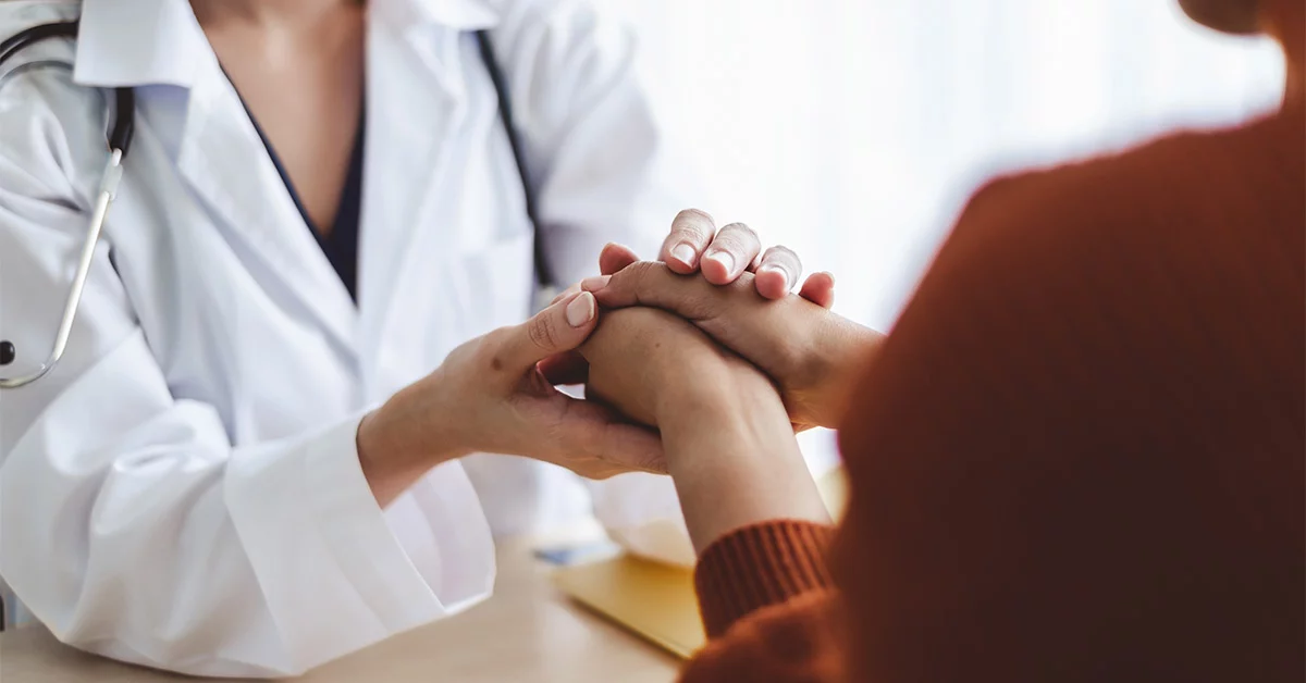 Woman doctor holding the hand of woman patient