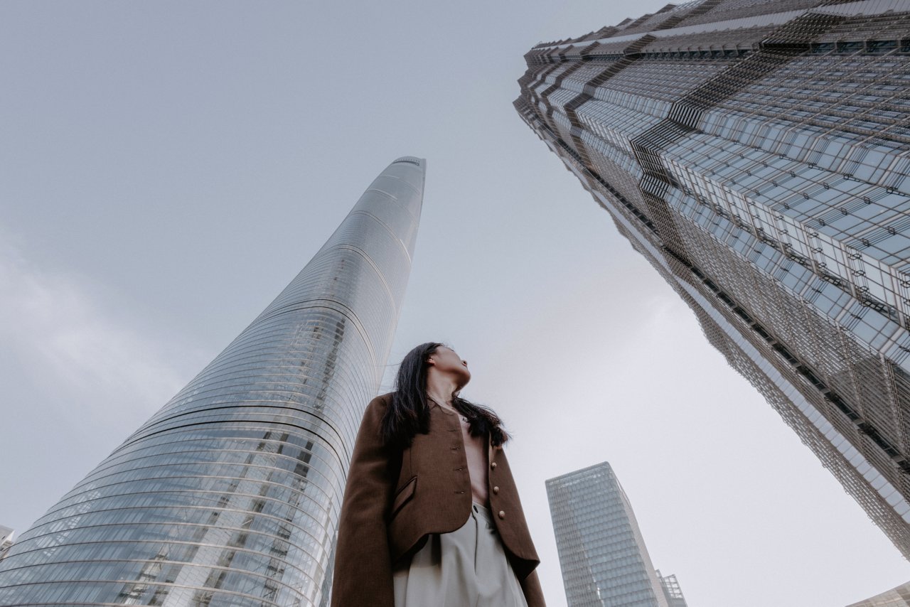 Confident Asian businesswoman standing under skyscrapers in Shanghai, China