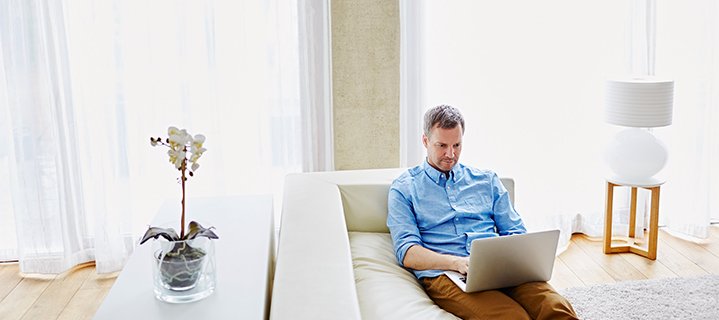 Man working on laptop while sitting on white couch 