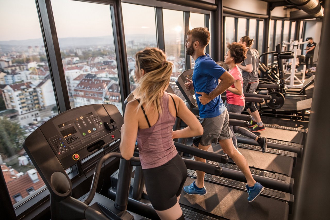 Young athletic people warming up while jogging on treadmills in a health club.