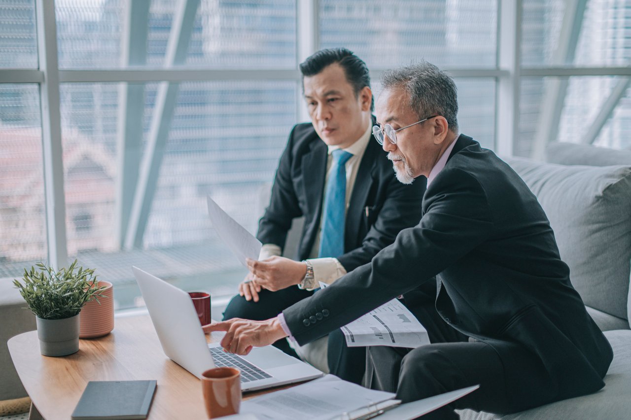 2 Asian mature businessmen discussion performance review business plan in office