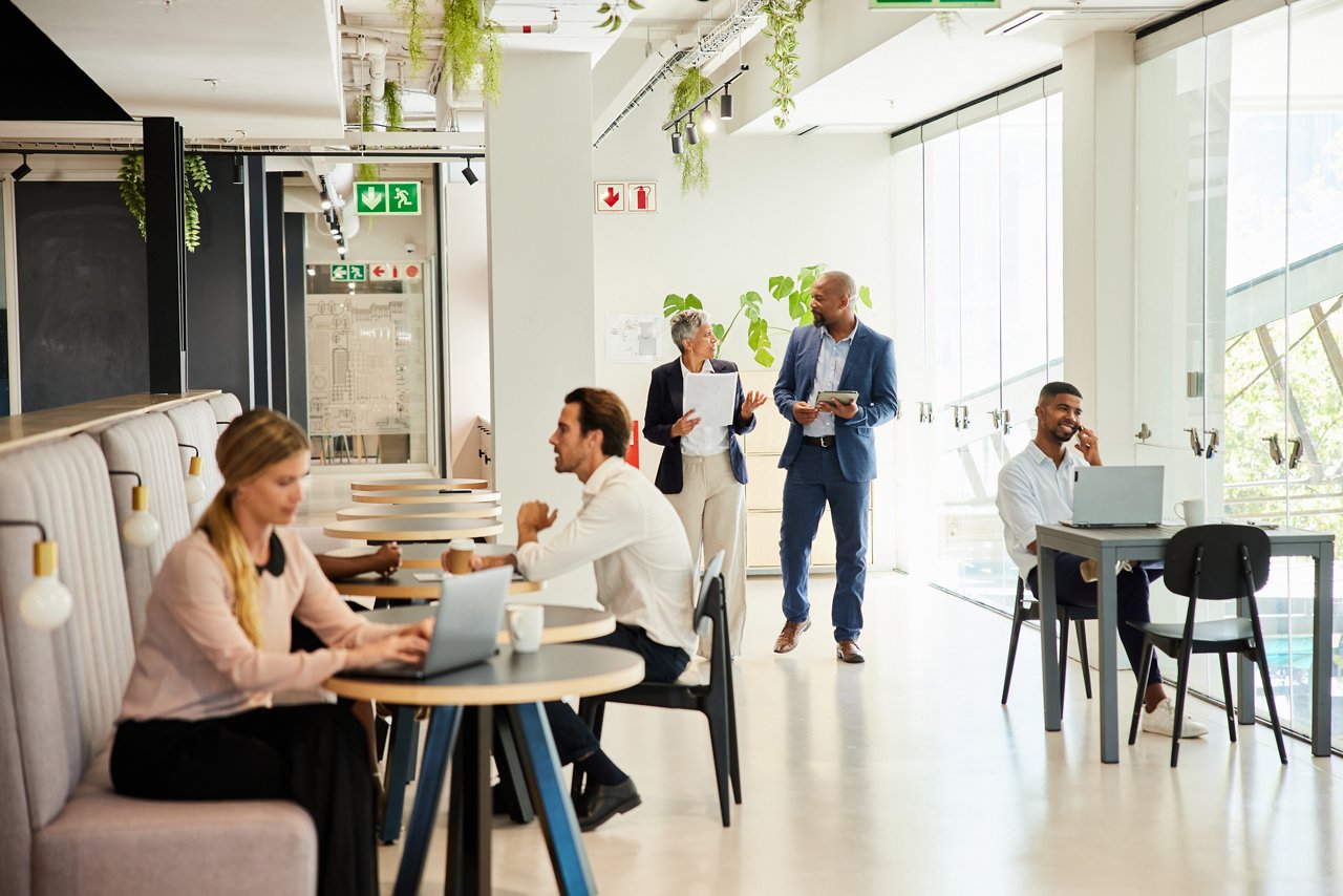 Diverse group of businesspeople talking together or working in the lounge area of a modern office building