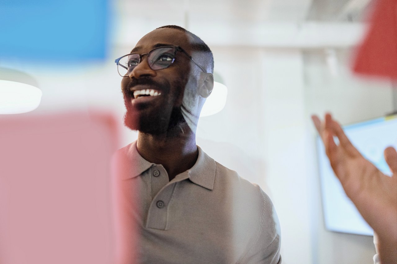 Portrait of a smiling black man presenting his ideas on a glass wall during a business meeting