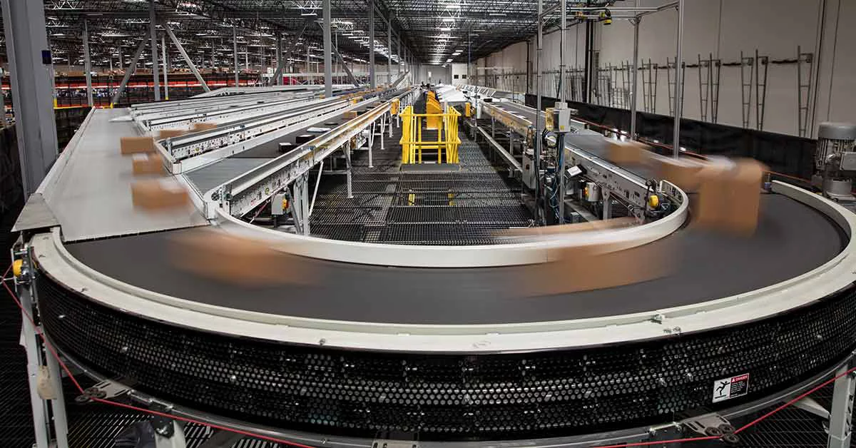Packages blur as they rush past on the complex conveyor belt system that sorts them for delivery at a large fulfillment center.
