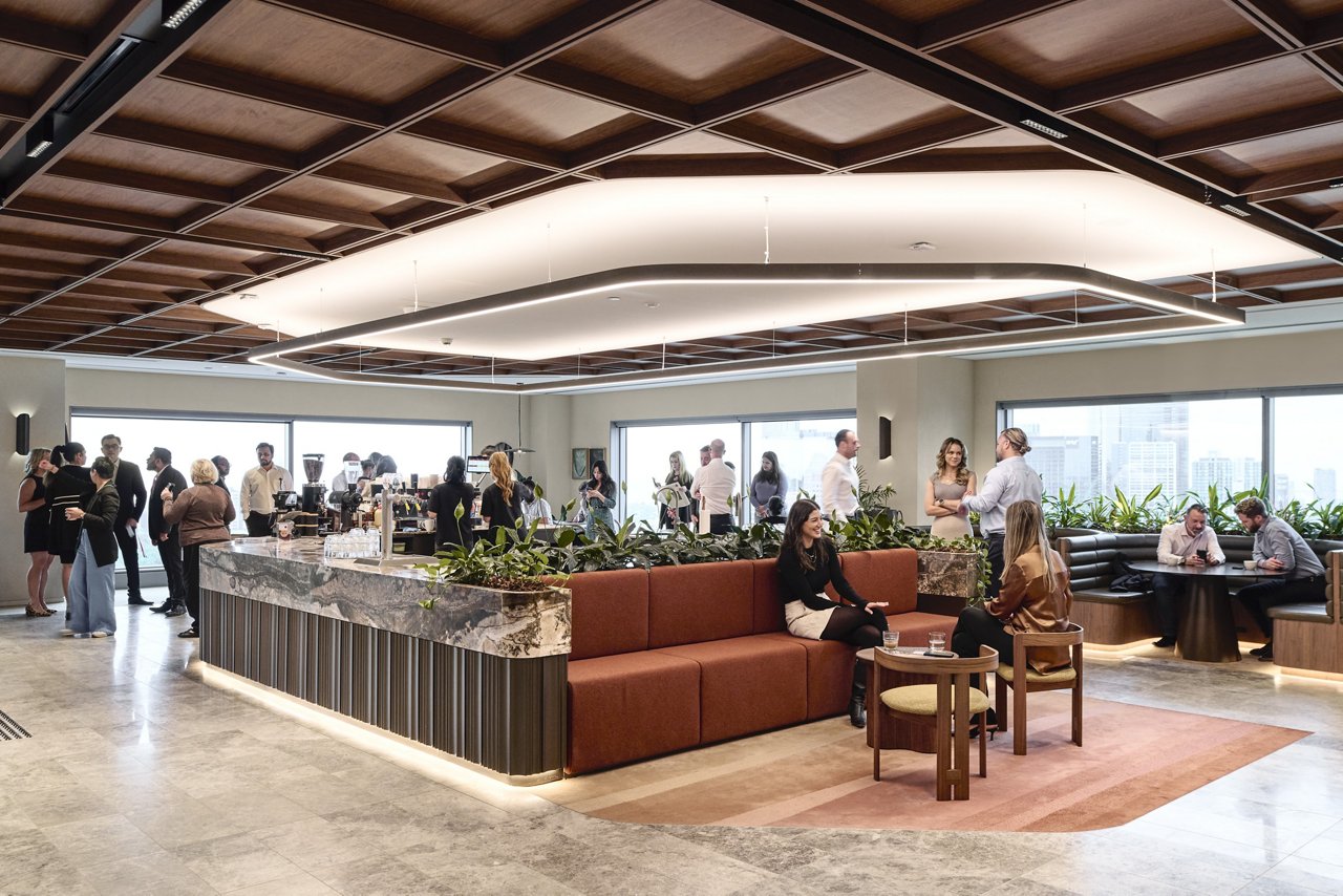 Modern office lounge with people networking and having conversations around a central coffee bar