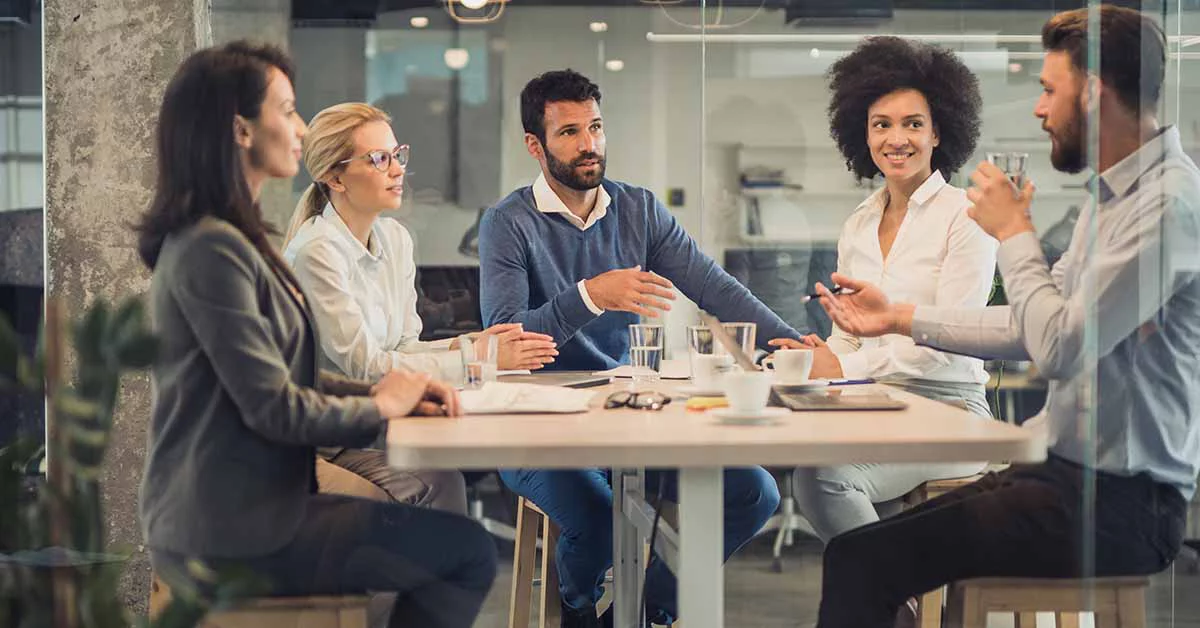 A diverse group of people engaged in conversation around a table.
