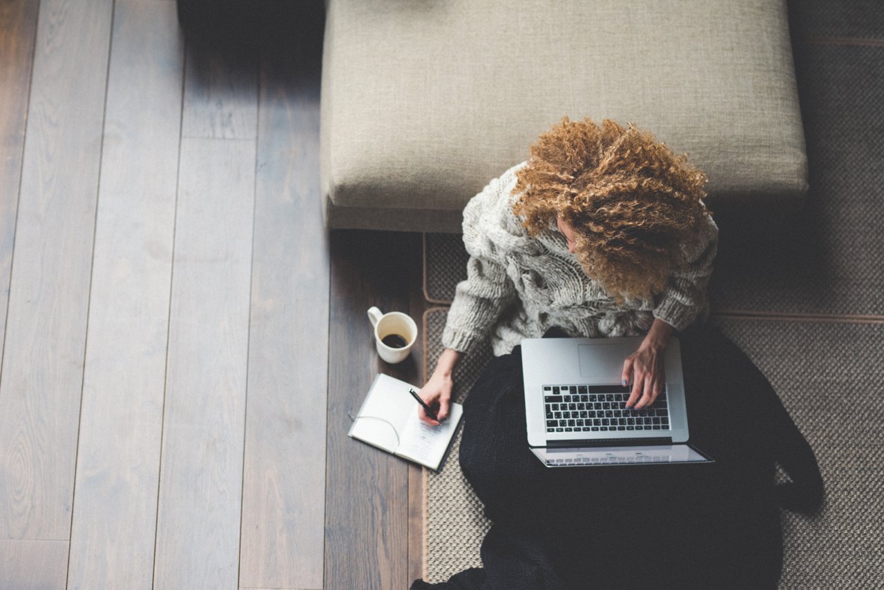 Overhead view of a person in a gray sweater working on a laptop