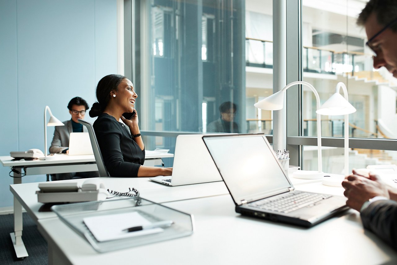 オフィスでテーブルの上にノートパソコンを開いたまま座っている女性