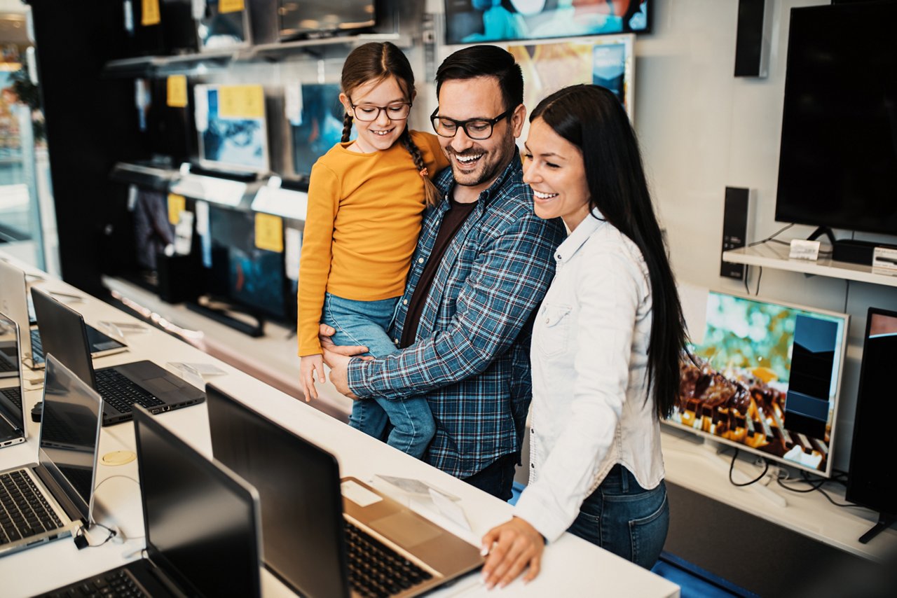 Happy family buying laptop in store.