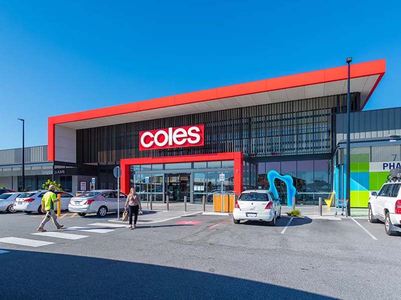 Modern Coles supermarket with distinctive red and gray exterior design, featuring large glass windows