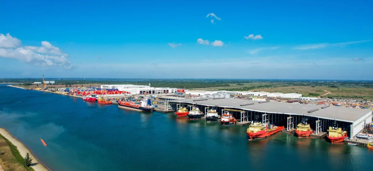 A panoramic view of the Port of Mauritius, showcasing ships docked and vibrant coastal scenery under a clear blue sky.