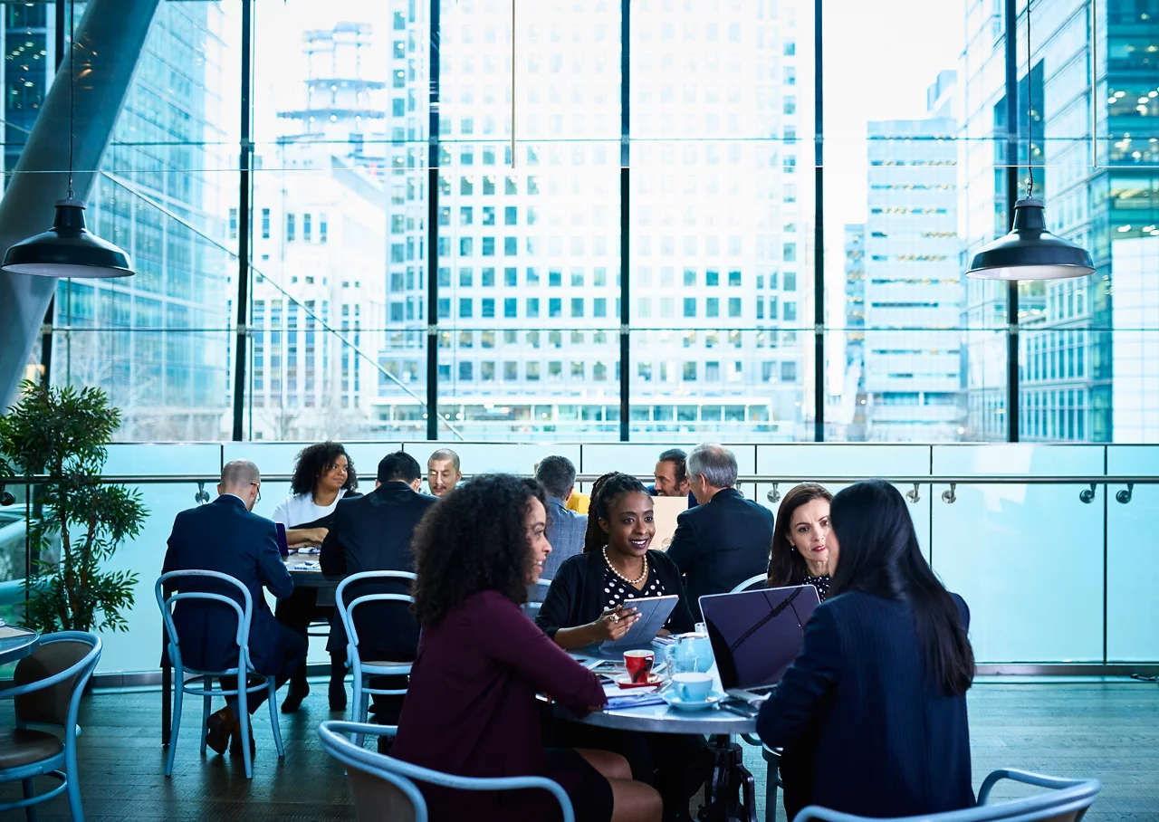  Diverse professionals collaborate in modern office space with city skyline view through large windows.