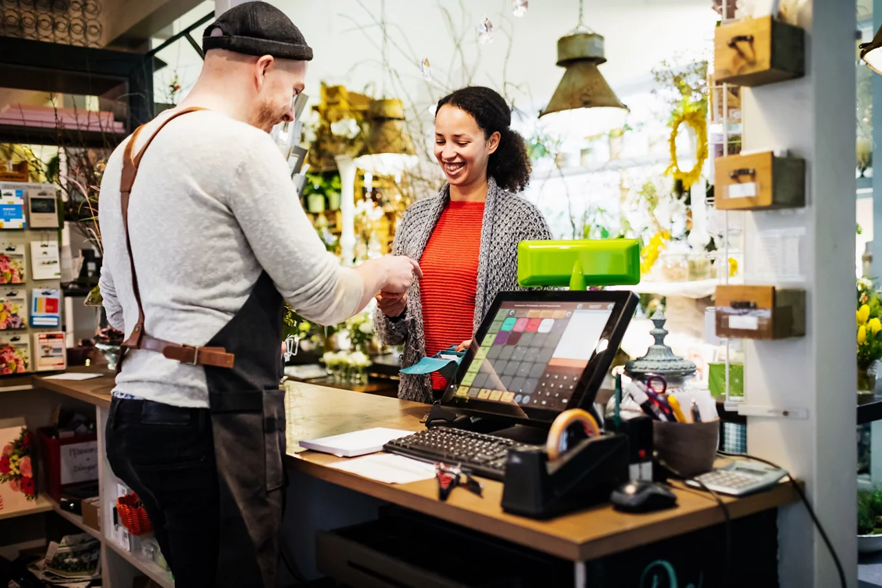 A florist serving one of his customers at his cash register as she pays for a purchase.