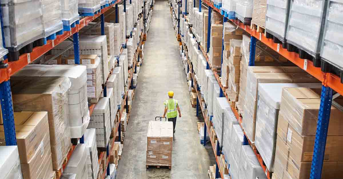 Worker Pulling Cardboard Boxes At Warehouse