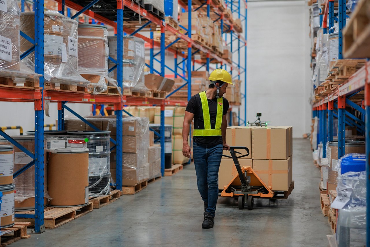 Asian male worker pushing an hydraulic hand pallet truck on a warehouse