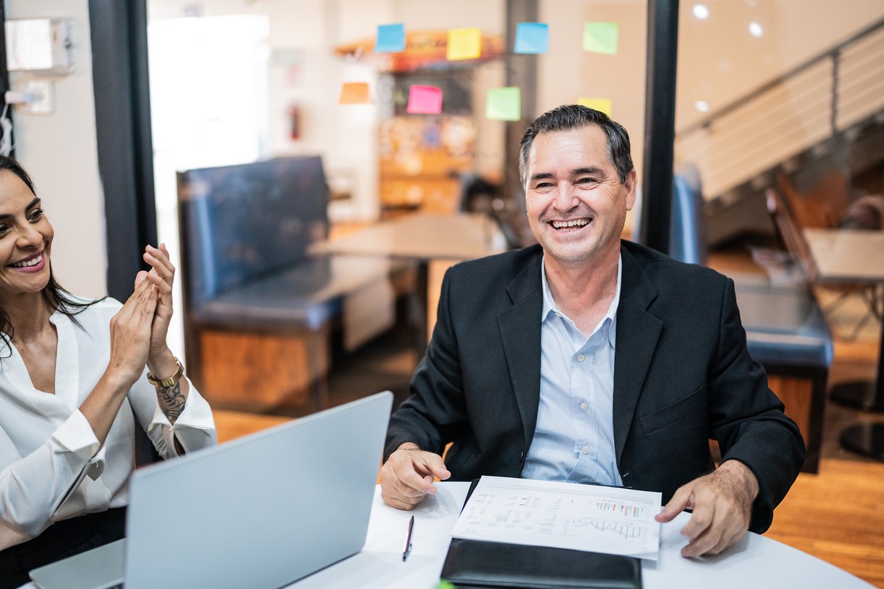 Mature businessman celebrating with his coworkers on a meeting at office