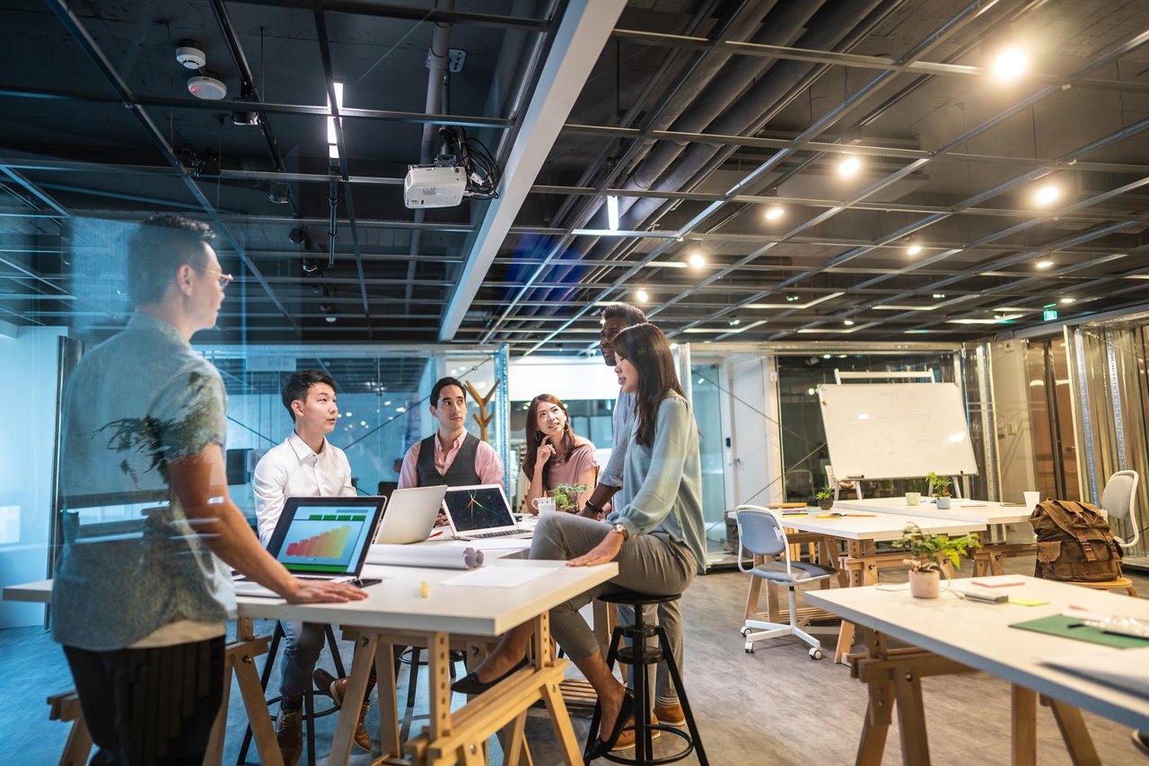 Group of young, modern people sitting on business meeting in modern coworking space and suggesting ideas for the best business strategy