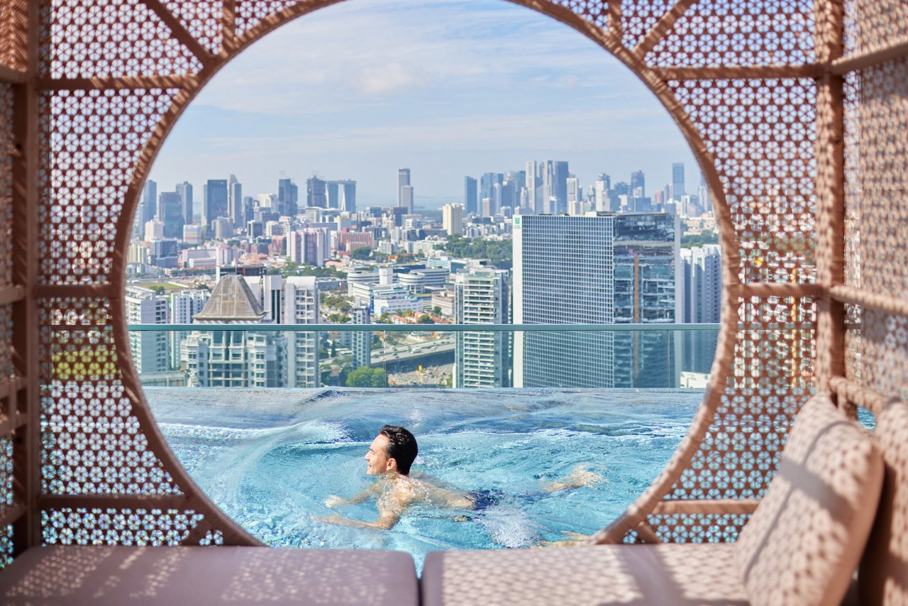 Attractive asian man swimming and doing laps at infinity pool with city skyline