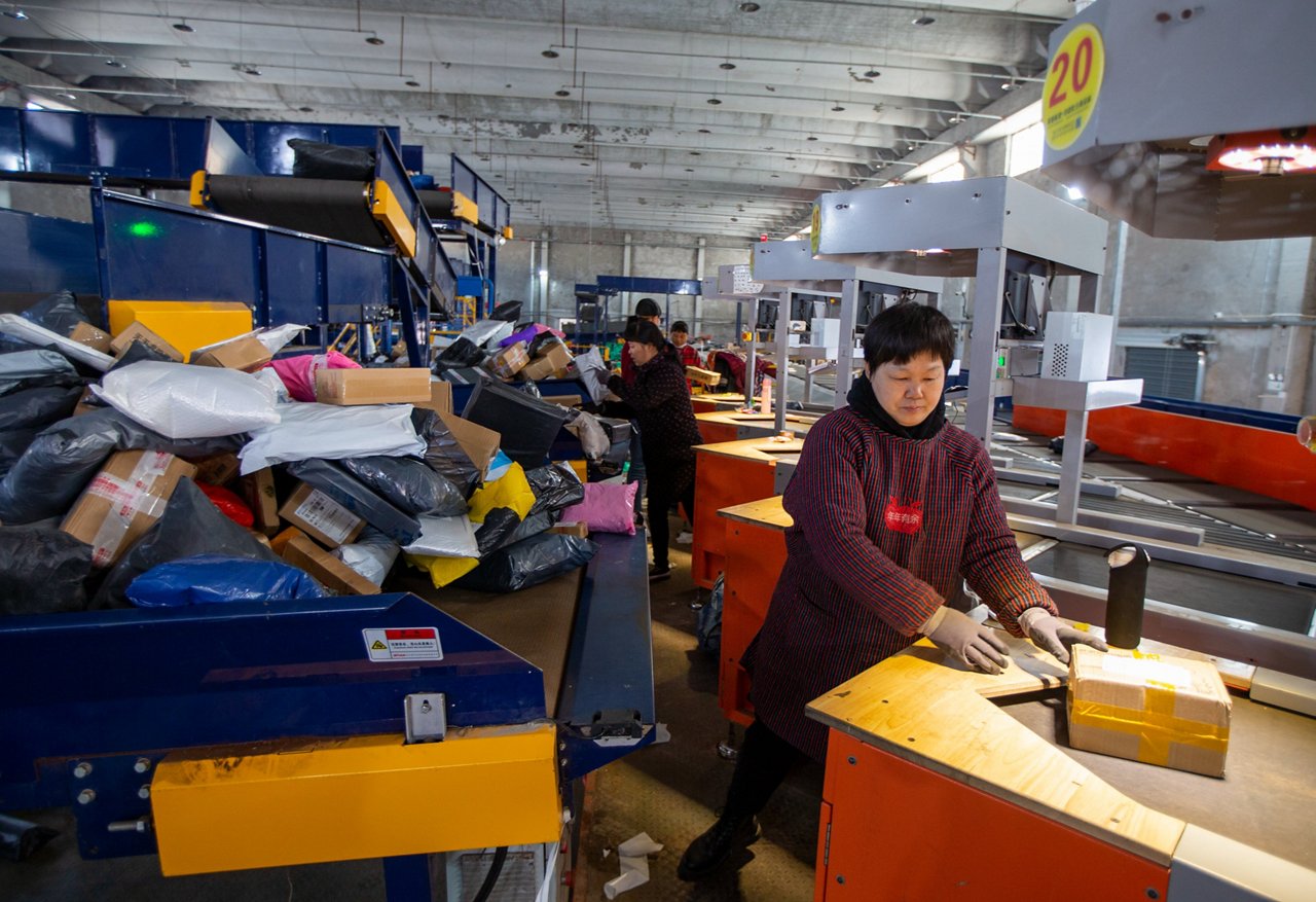 Workers sort packages on an assembly line at an express delivery distribution center