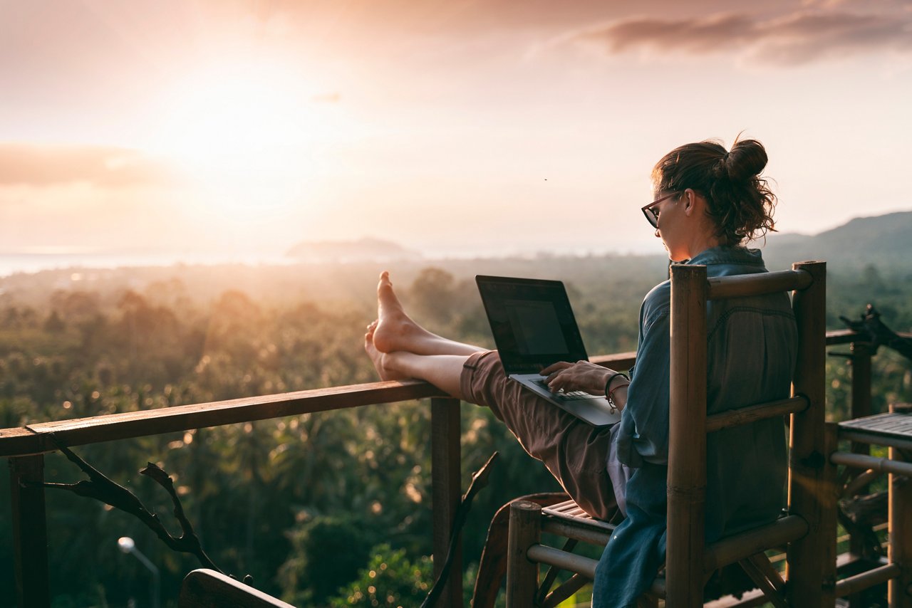 Young girl sitting in balcony and working on laptop