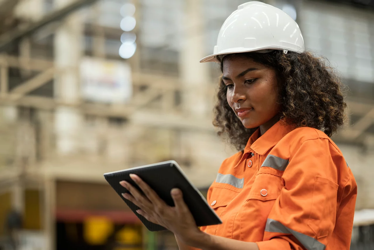 Shop Floor CAfrican American Production Control Engineer holding a tablet and standing in production line