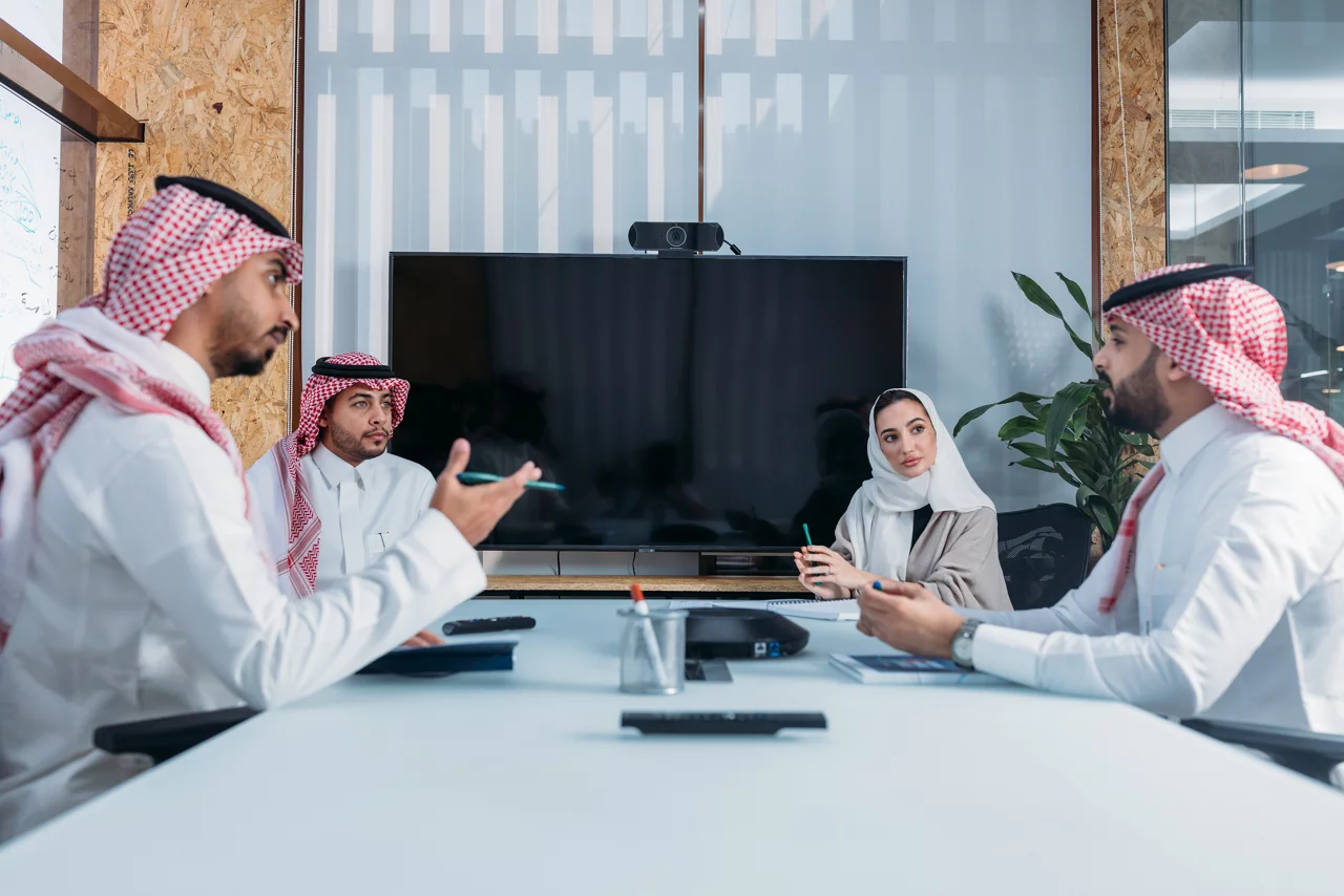 اجتماع عمل مهني يجري في قاعة مؤتمرات حديثة مع أربعة أشخاص