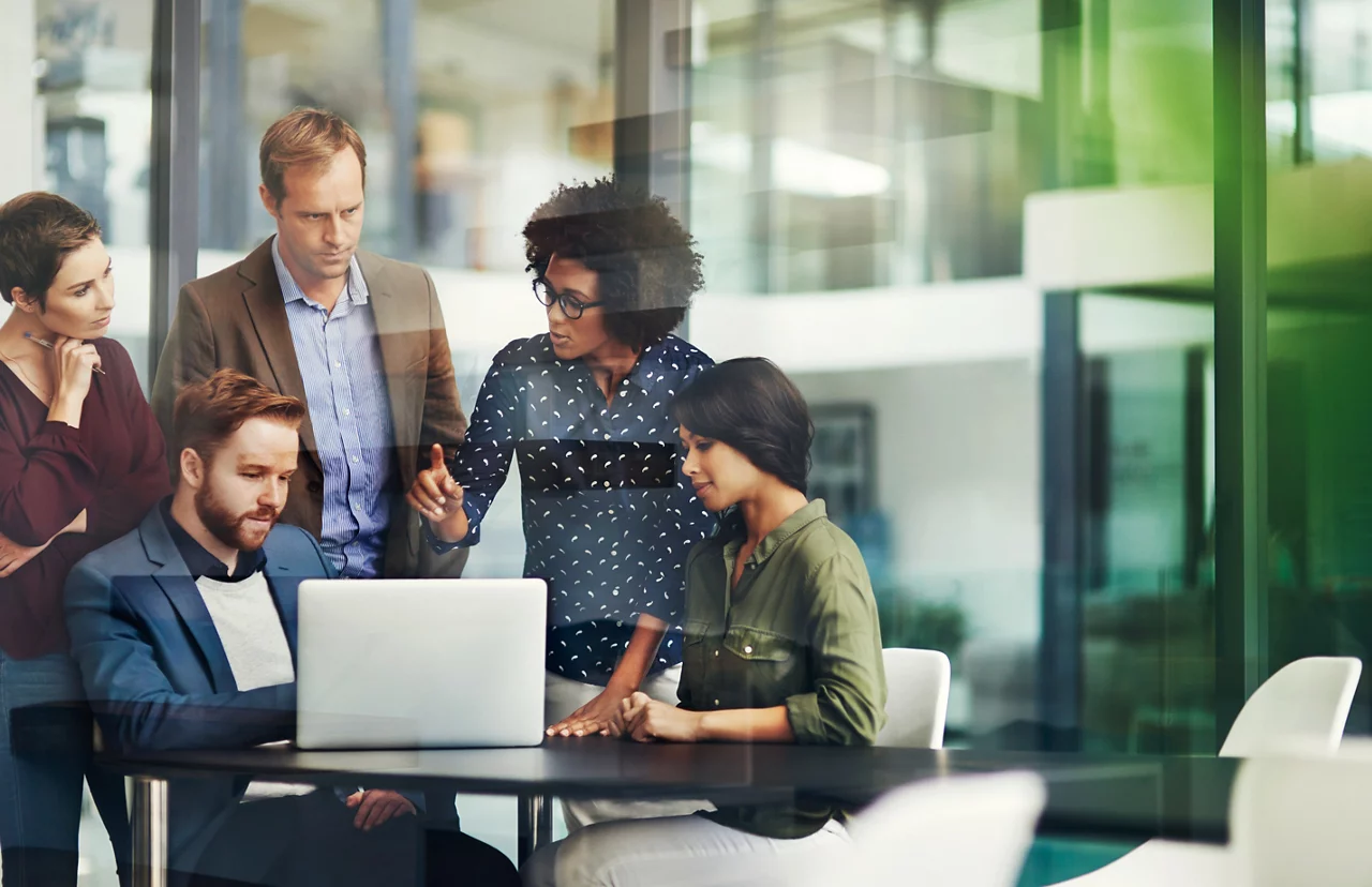 Shot of a group of colleagues using a laptop together at work
