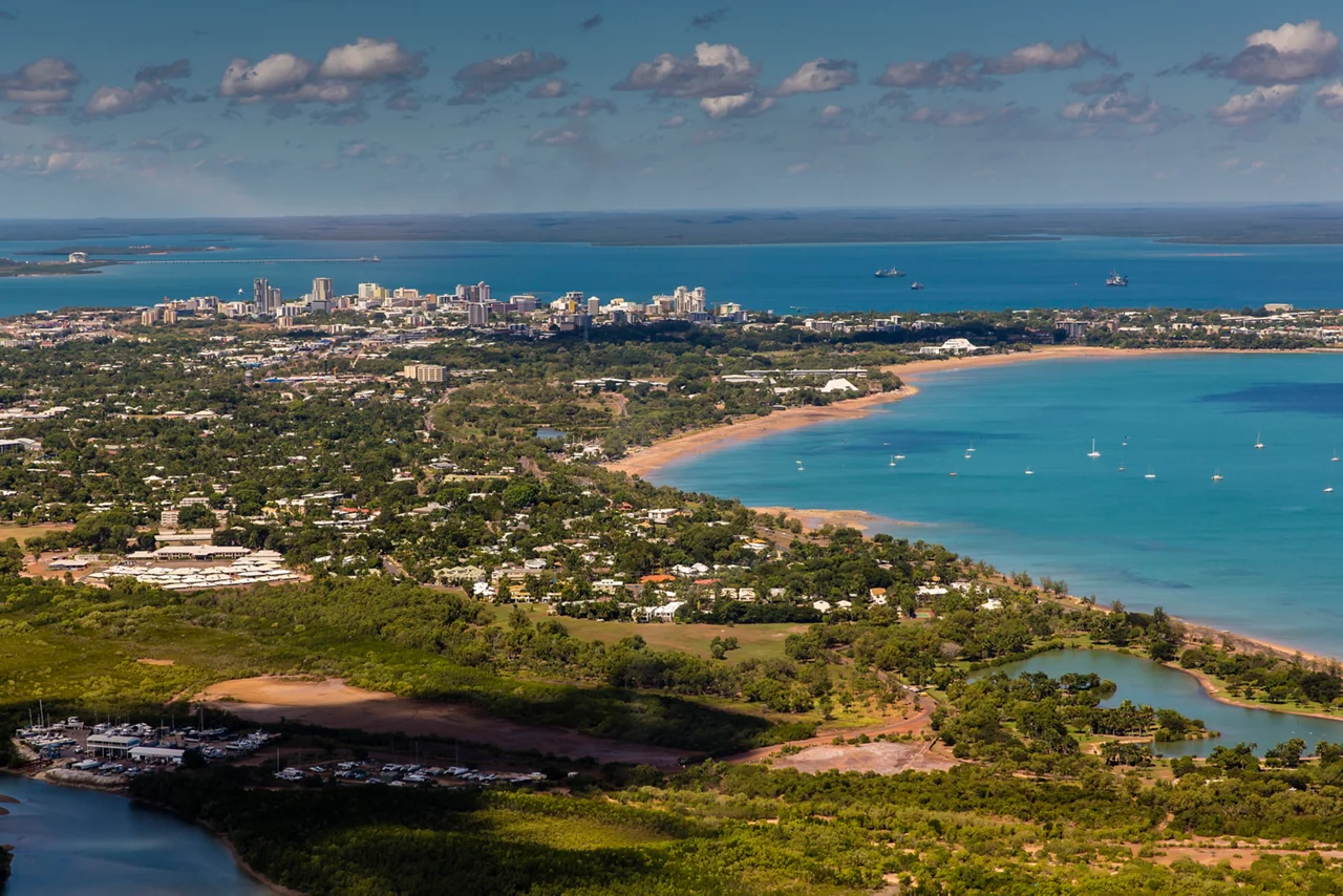 A sweeping aerial view of Darwin, showcasing the city's coastal business district, sandy beaches, and vibrant harbor.