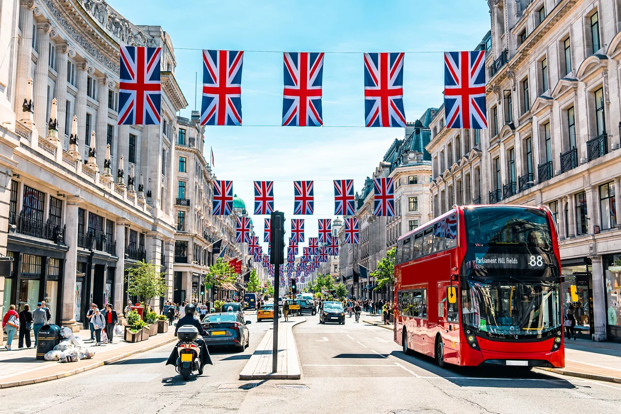 British flags decorating Regent Street in London with iconic red double-decker bus and historic architecture.