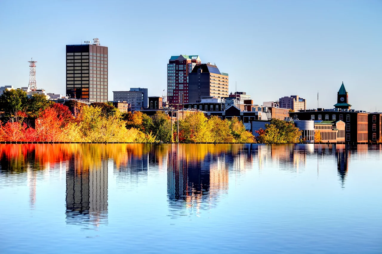 Manchester New Hampshire skyline along the banks of the Merrimack River in autumn.
