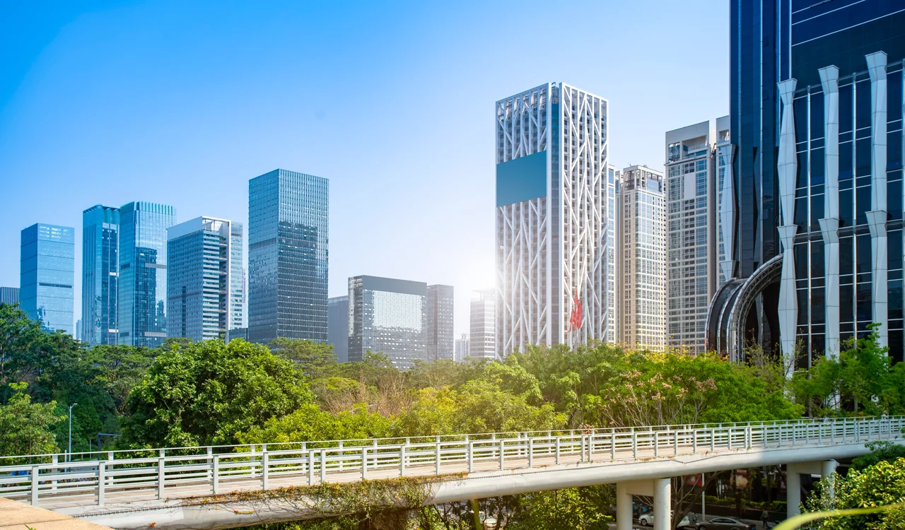 现代城市天际线，玻璃摩天大楼，前景绿树，人行天桥，蓝天下明媚的阳光。