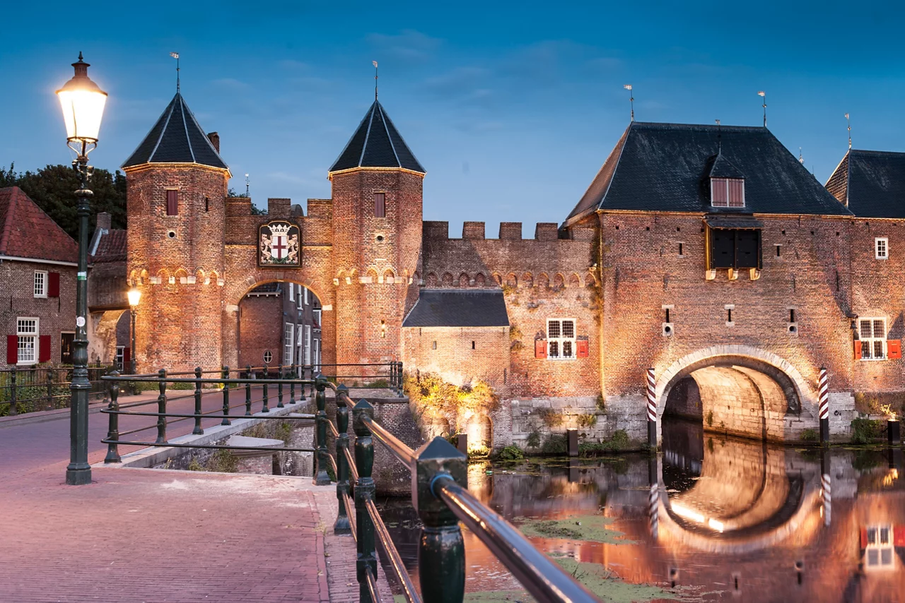Medieval brick city gate Koppelpoort to Dutch fortress city Amersfoort rounded by Eem river on the evenong, Netherlands, Province Utrecht.