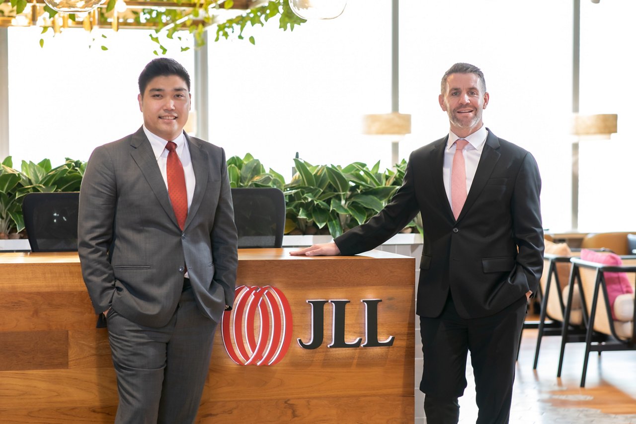Two men standing at JLL Thailand front office
