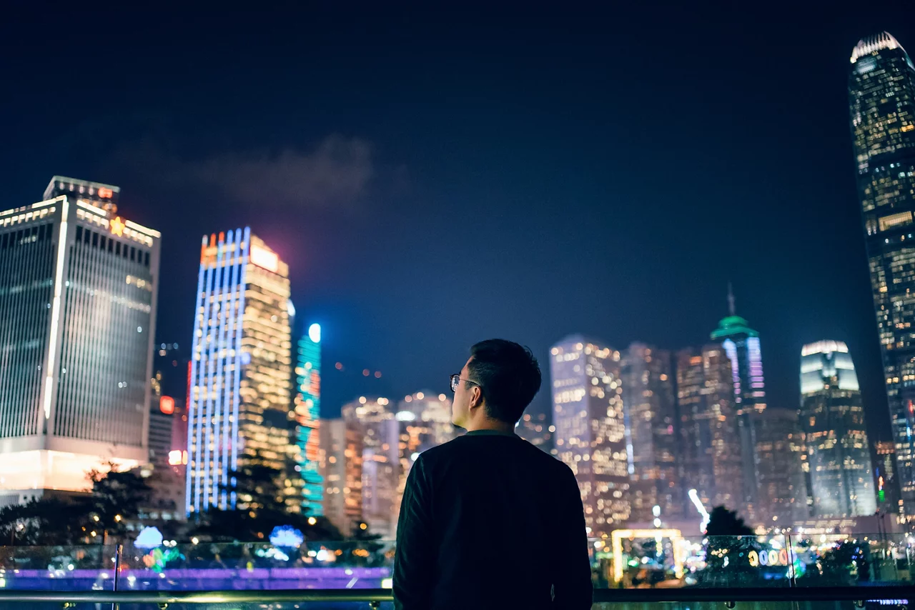 Rear view of young man looking towards the prosperity of Hong Kong city skyline in downtown financial district
