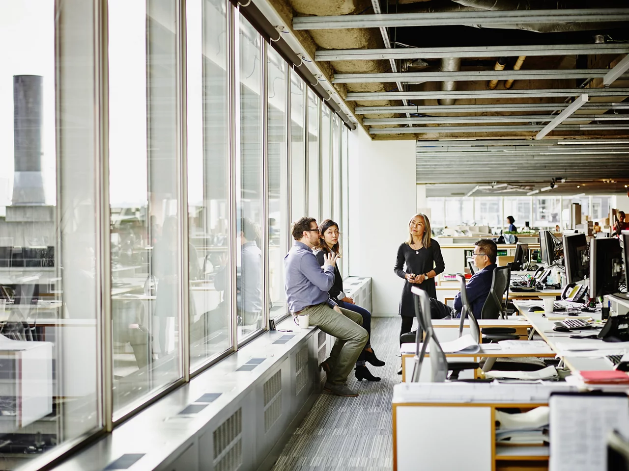 Group of businesswomen and businessmen having team meeting at workstation in office