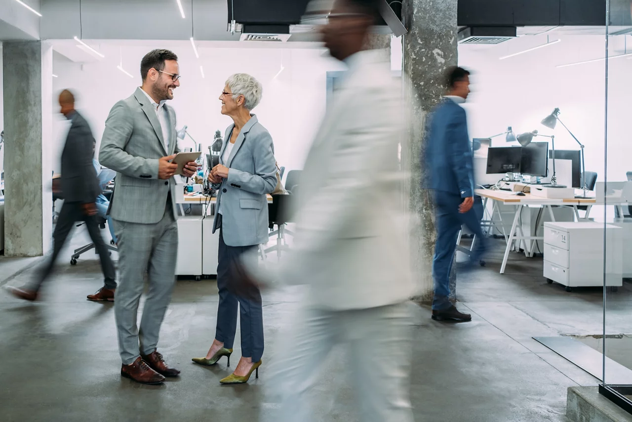 two colleagues are talking with each other about their work at the office.