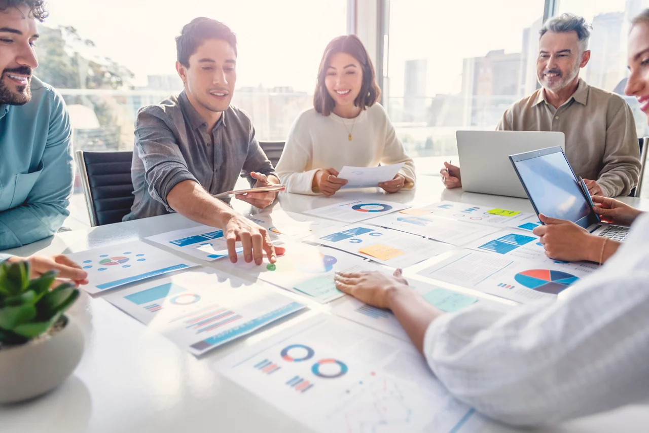 Multi racial diverse group of people working with Paperwork on a board room table at a business presentation or seminar. 