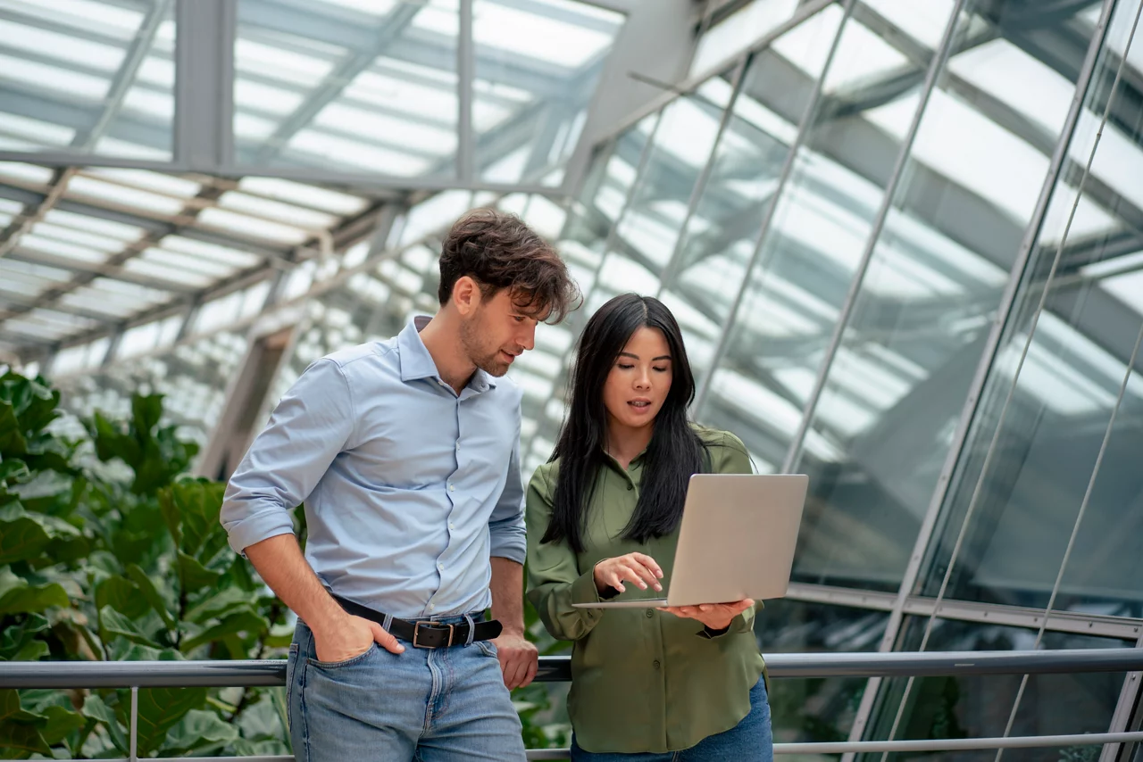 Businesswoman sharing laptop with colleague working in corridor