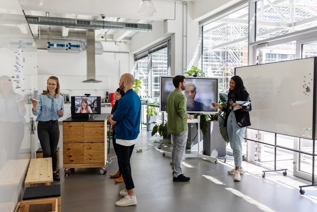 Startup business team working on different projects with colleagues joining in via video call. Group of multi-ethnic people having meetings in the hybrid office.