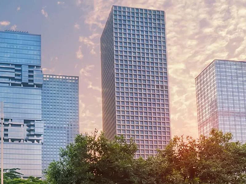 A skyline of tall buildings silhouetted against a vibrant sunset in a bustling city.