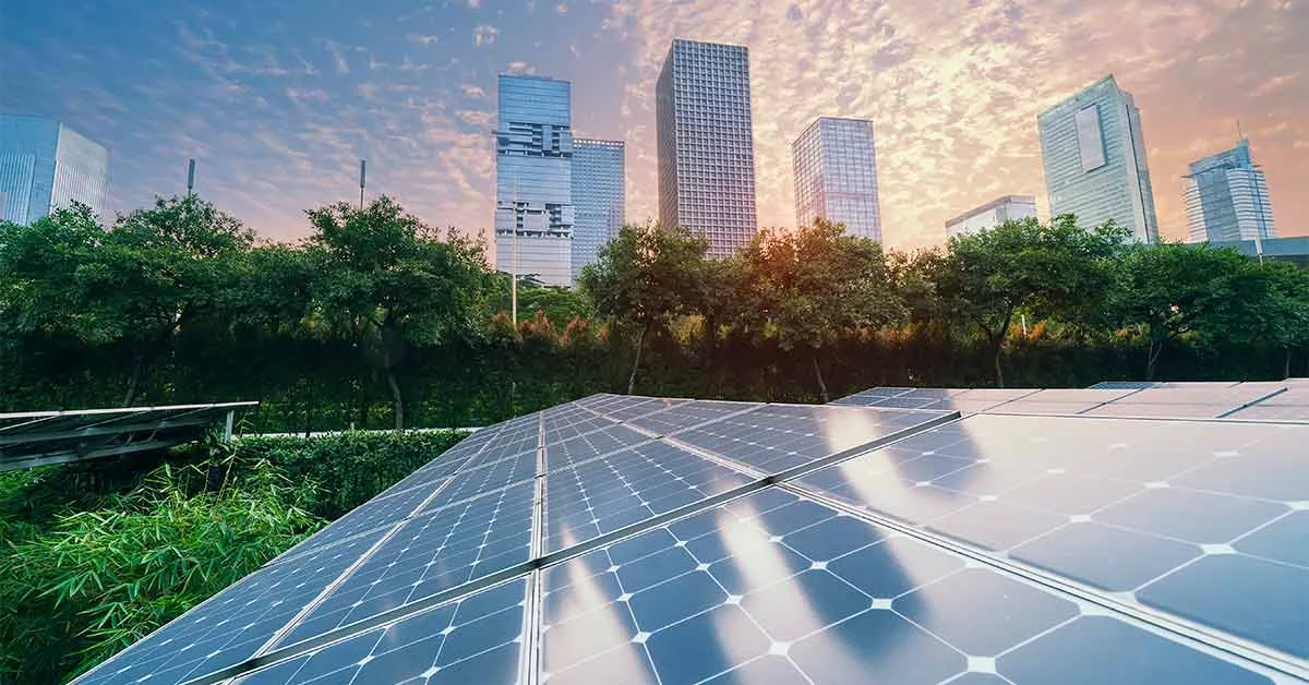 Paneles solares y edificios comerciales con una puesta de sol como fondo