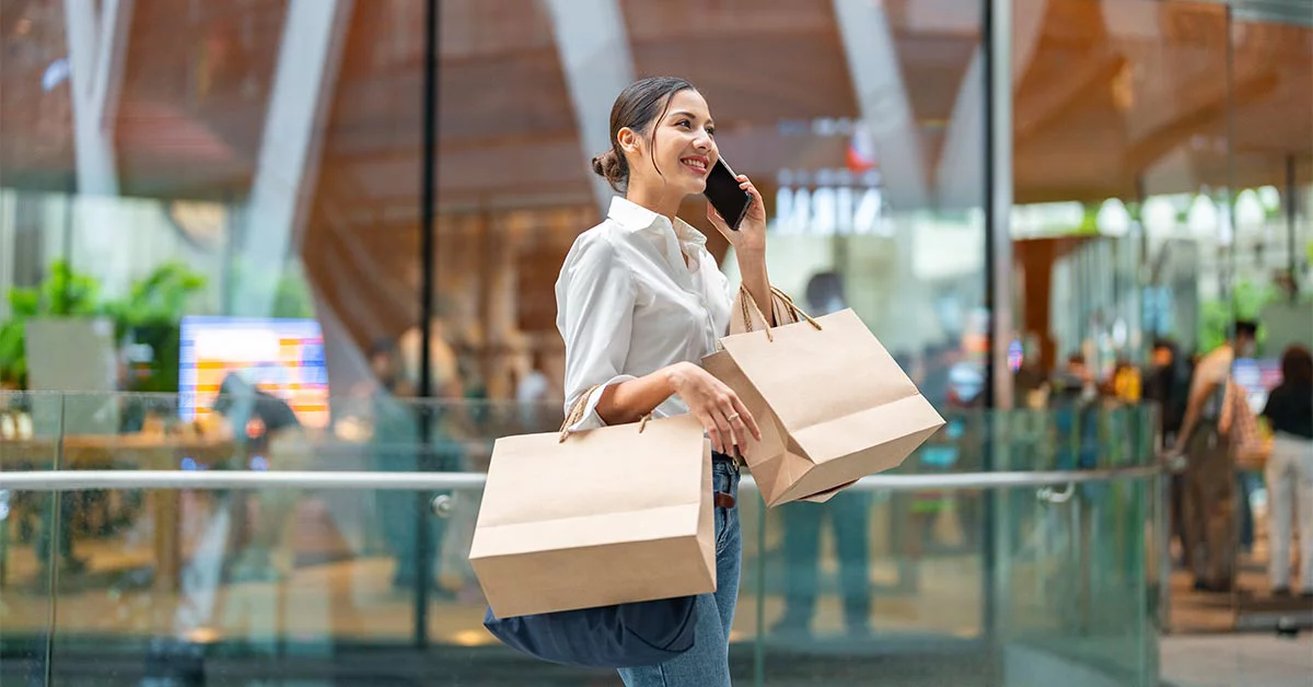A woman holding phone and shopping bags