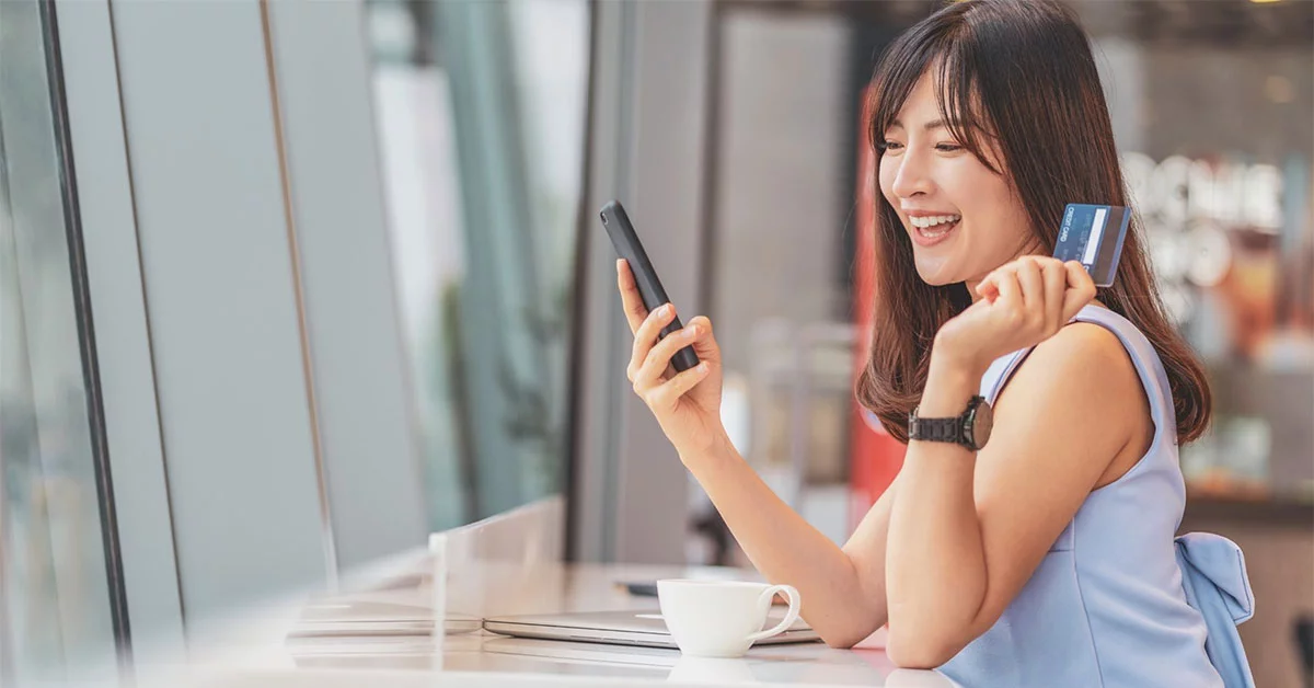 A girl holding a phone and card