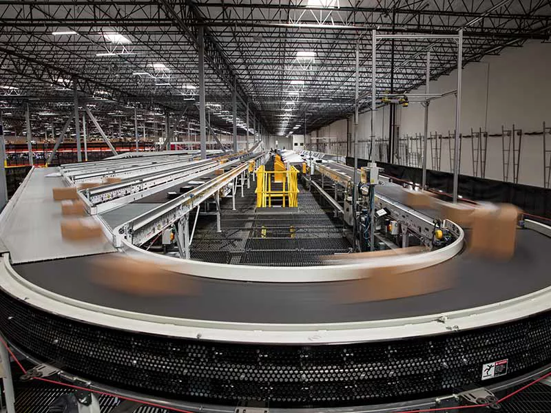 Packages blur as they rush past on the complex conveyor belt system that sorts them for delivery at a large fulfillment center.