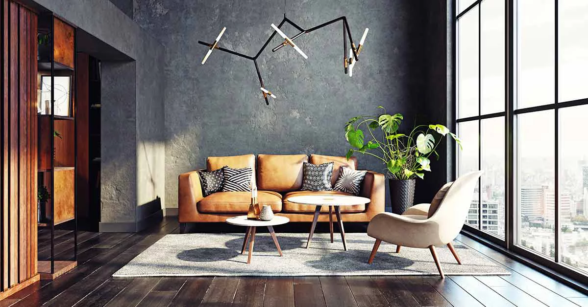 Mid-century modern chair with a blanket and a large sofa with colorful cushions in a spacious living room interior with green plants and white walls. Real photo.