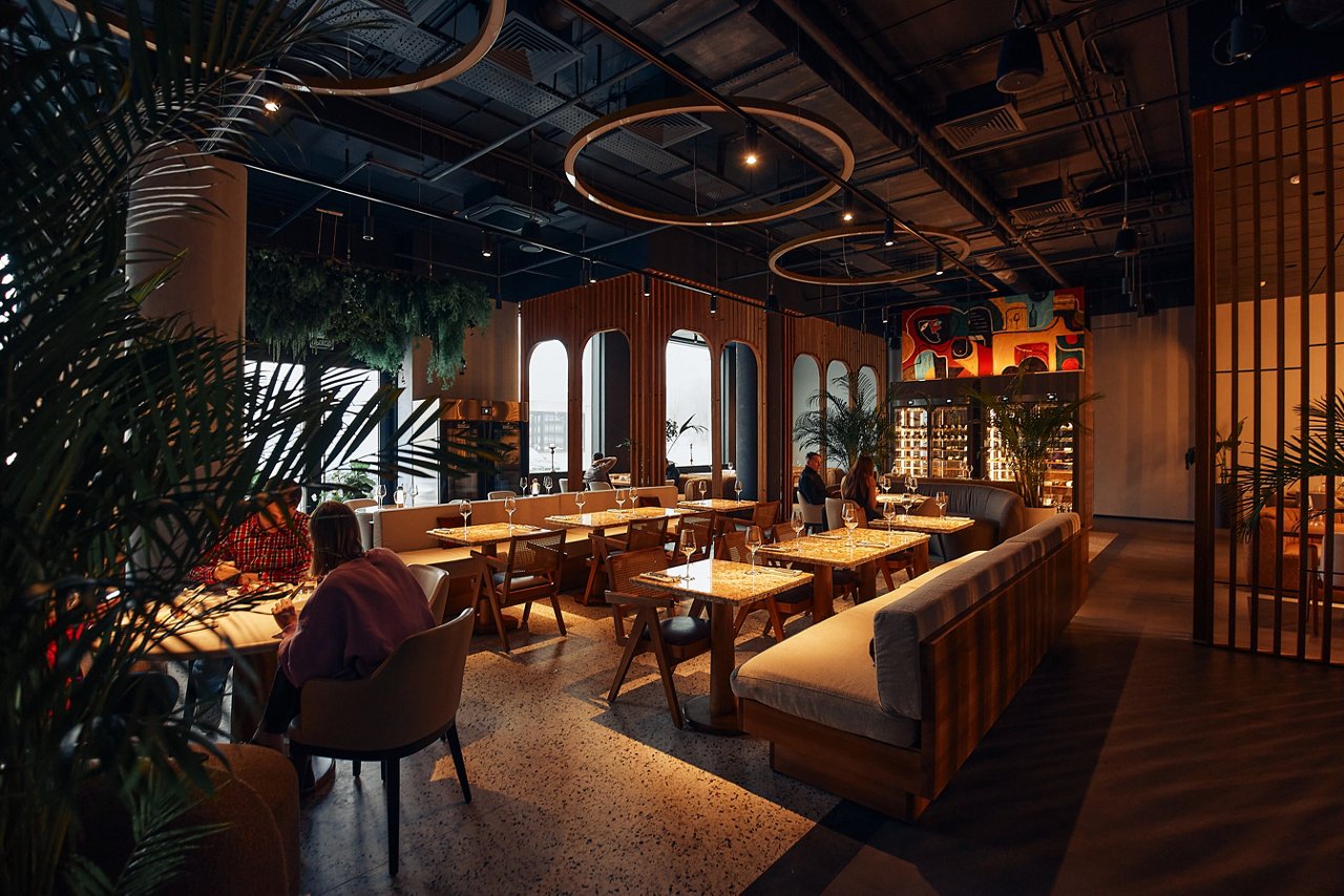 Elegant decorated restaurant with rich visitors looking through menu with big variety of dishes. Cozy day in luxurious place for relaxation
