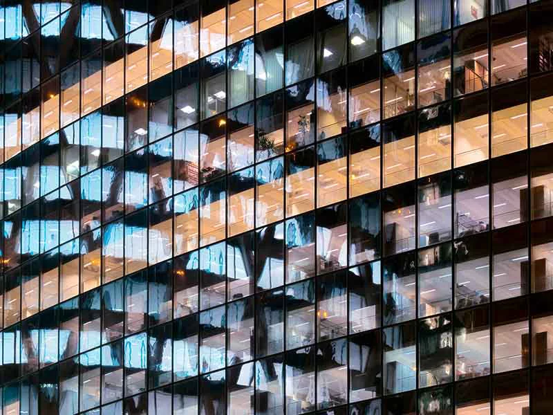 A glass surface reflects a contemporary building