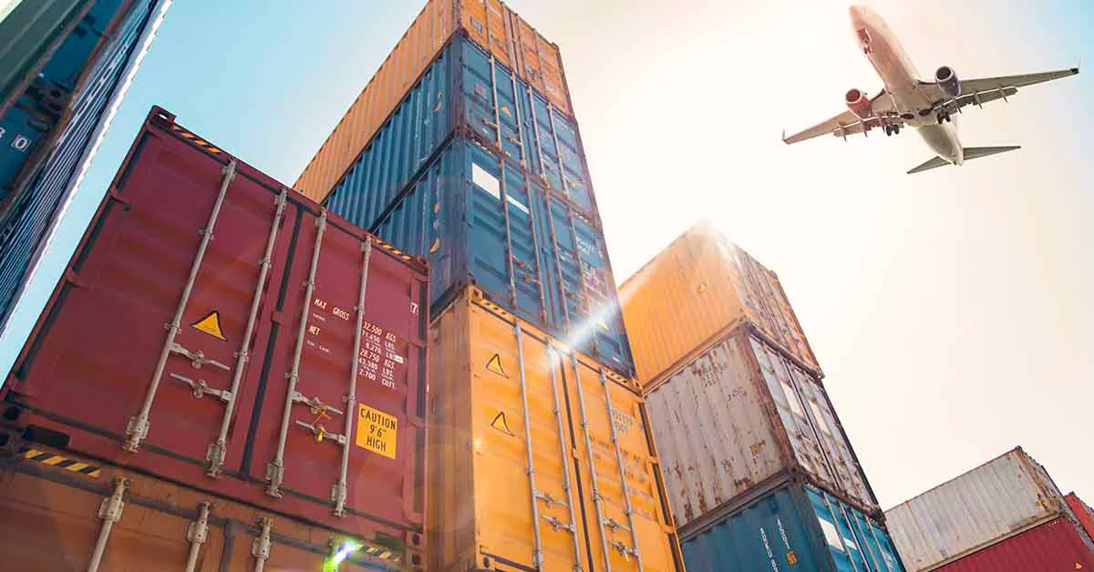 A plane flying over a stack of shipping containers
