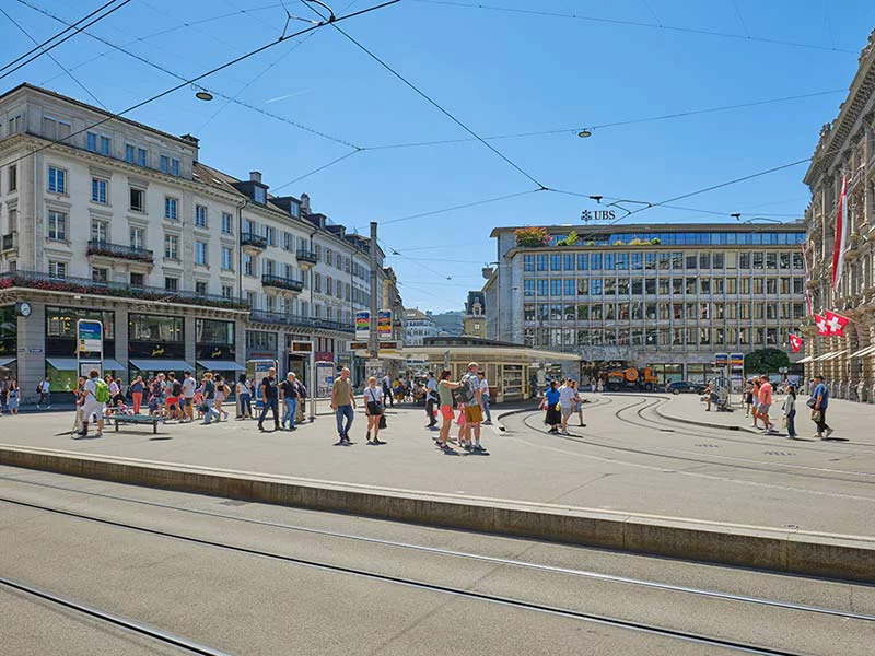 A bustling city square filled with people walking and standing